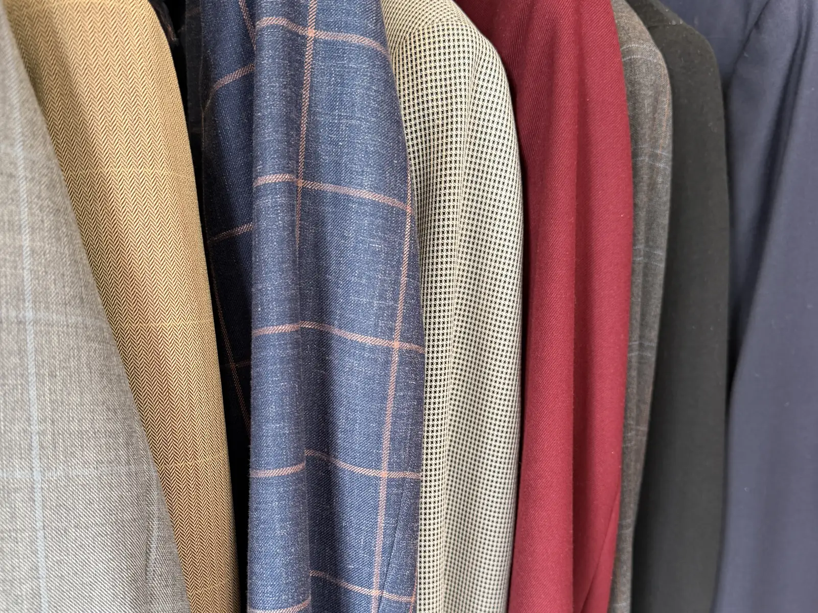 Sport jackets on the rack at Komal's Suits, including an oxblood jacket and a blue windowpane