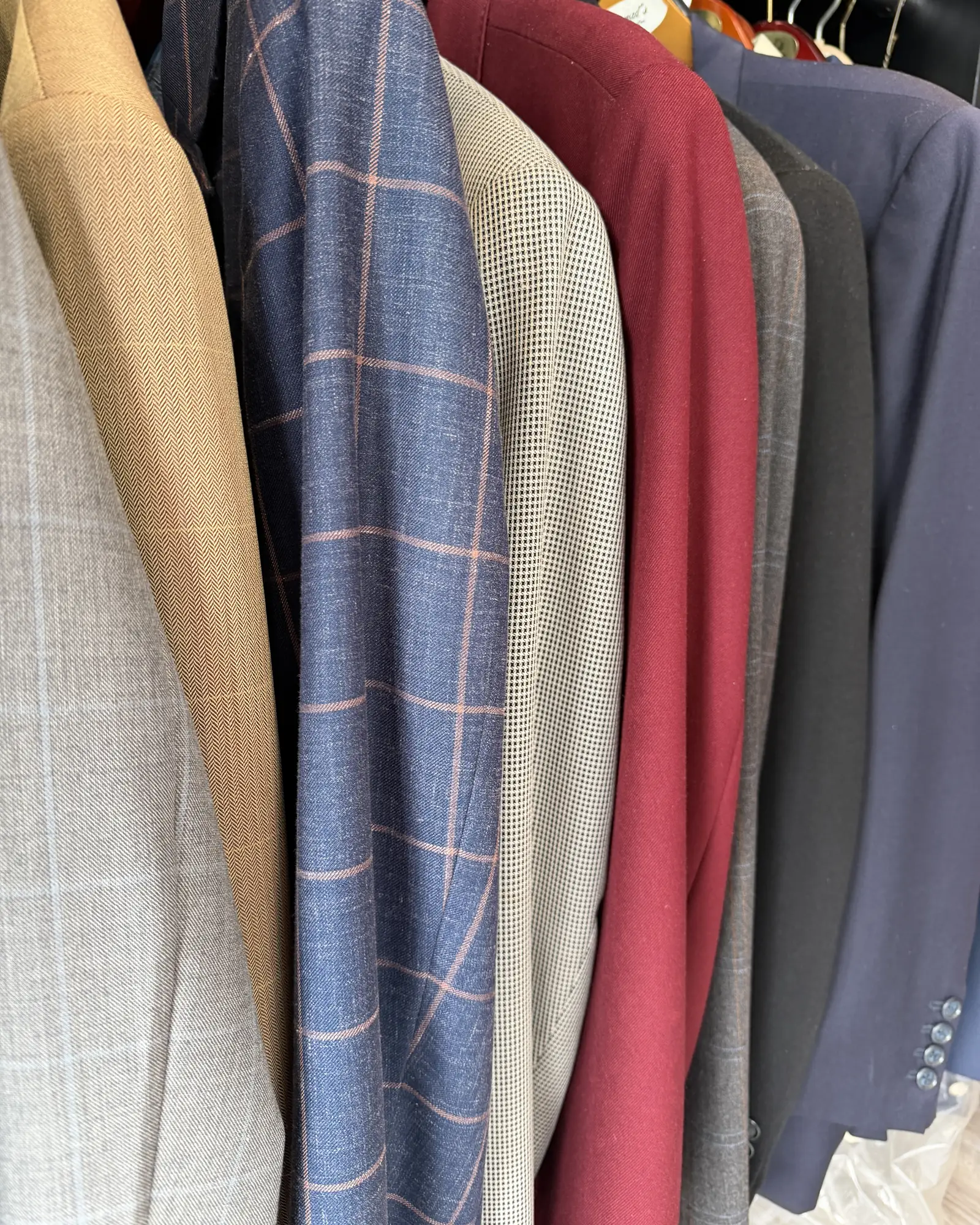Custom jackets on the rack at Komal's Suits: herringbone, a blue windowpane, houndstooth and oxblood
